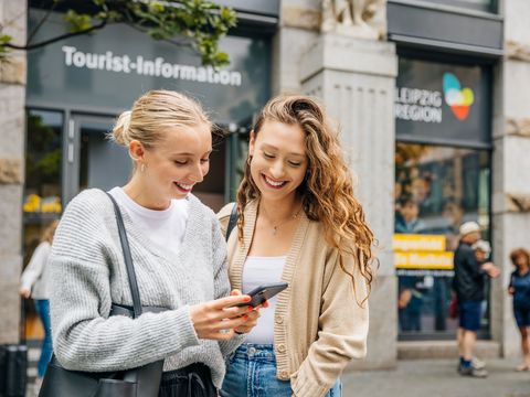 Zwei Frauen stehen vor der Tourist-Information in Leipzig.