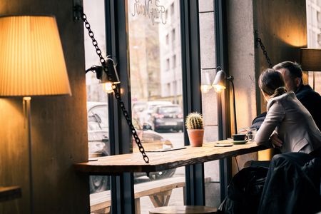 Ein Paar sitzt nebeneinander am Fensterplatz im Café Franz Morish und unterhält sich bei einer Tasse Kaffee..